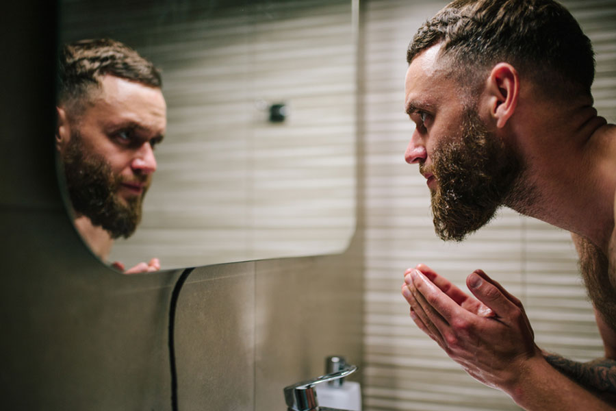 A bearded man washes his face