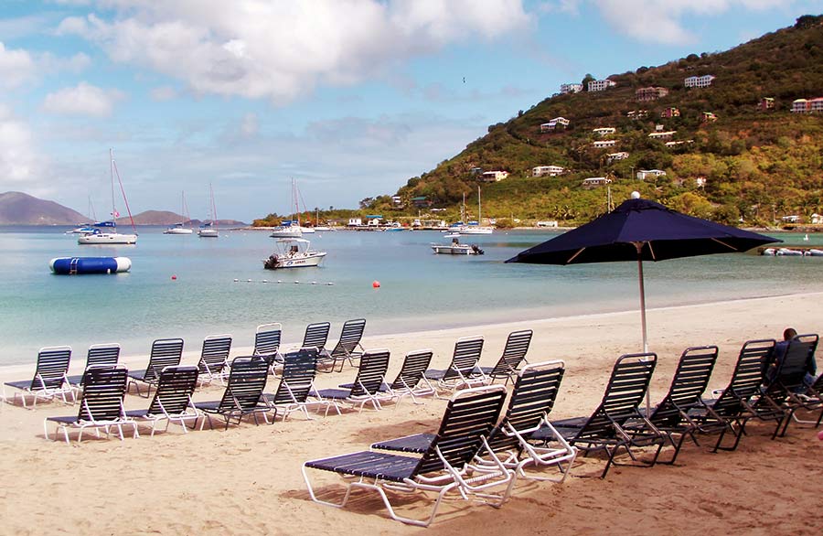 A view of empty beach chairs near water in Tortola