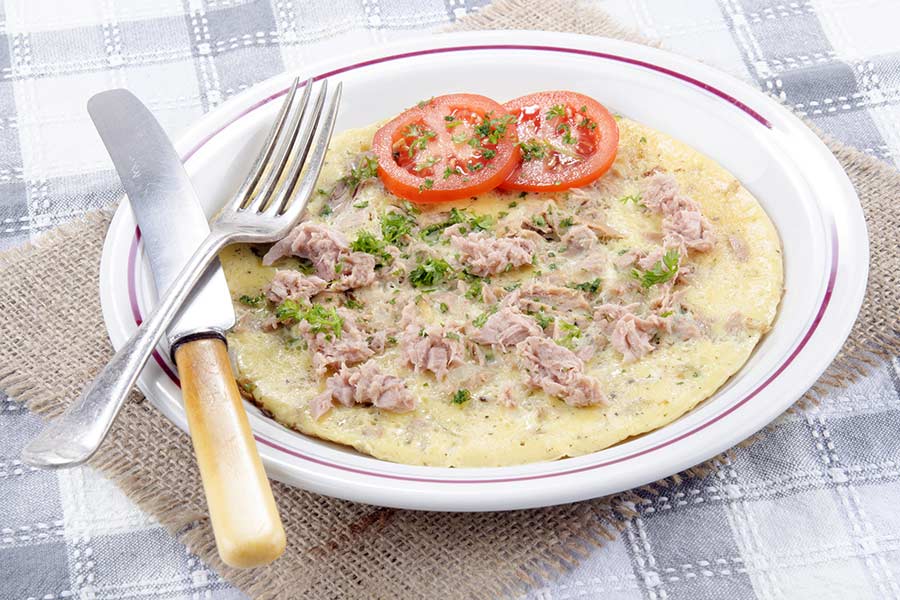 A dish of omelette tuna tomato parsley on plate